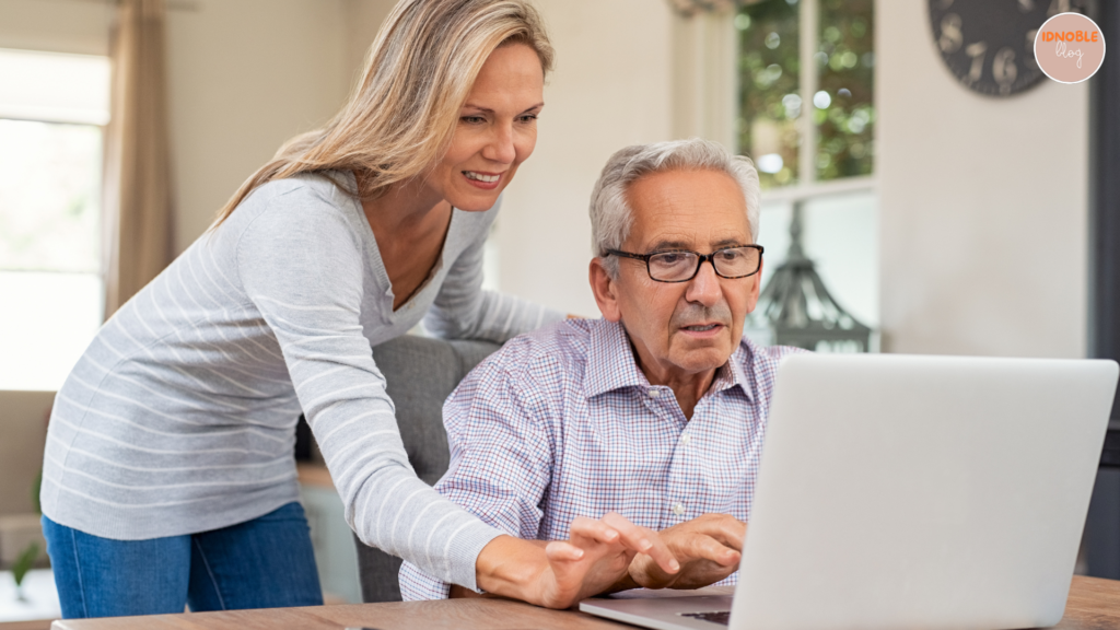 A picture of a family member helping a senior with online banking on a tablet or laptop